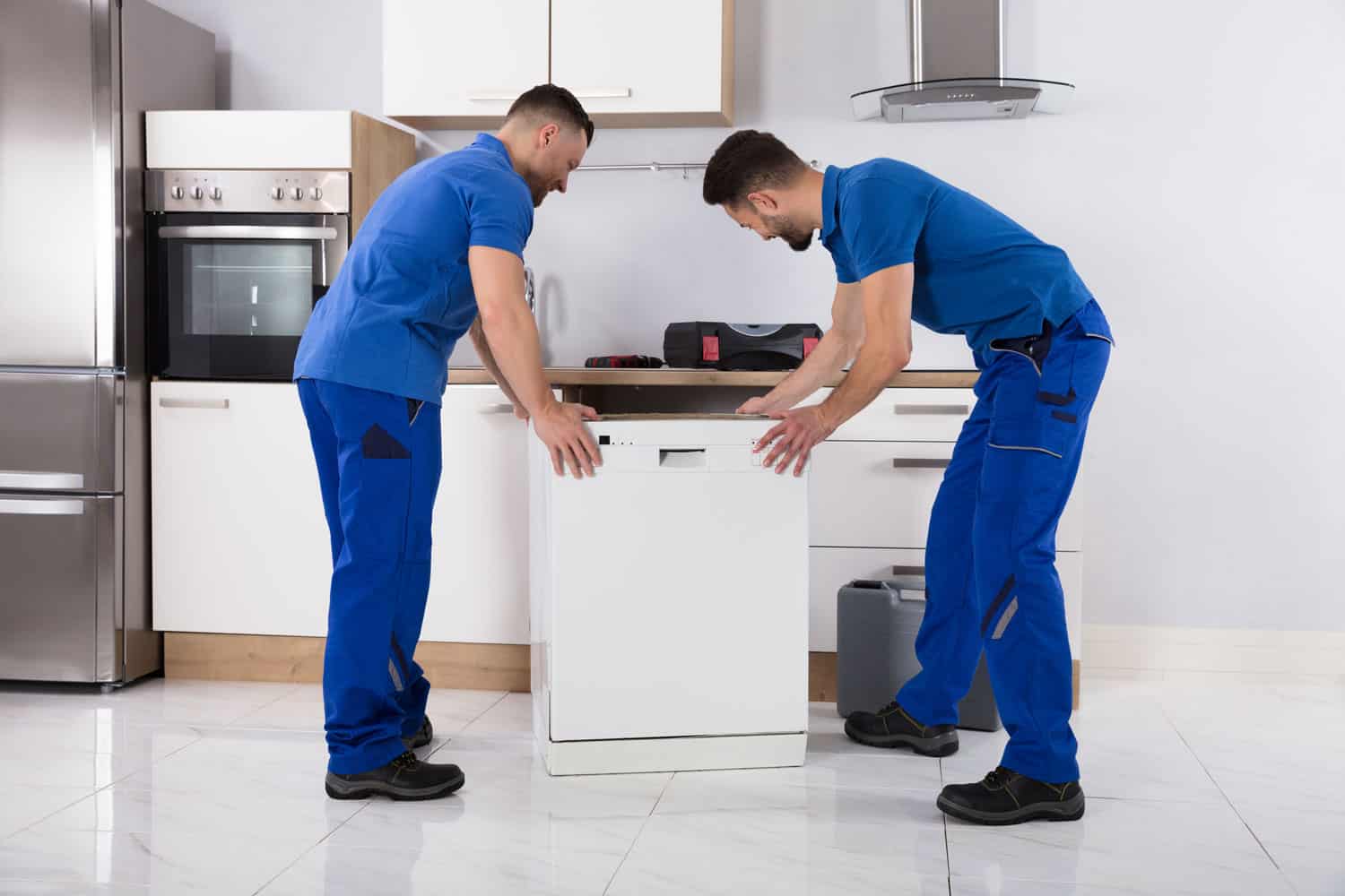两个穿着制服的年轻男性搬运工在厨房里放置洗碗机bd手机下载