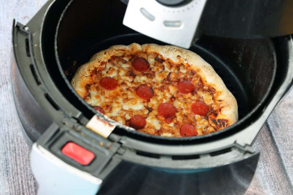 切成薄片的意大利辣香肠披萨，浇上浓郁的番茄酱、融化的磨碎的马苏里拉奶酪和圆形的意大利辣香肠，盛在空气煎锅里