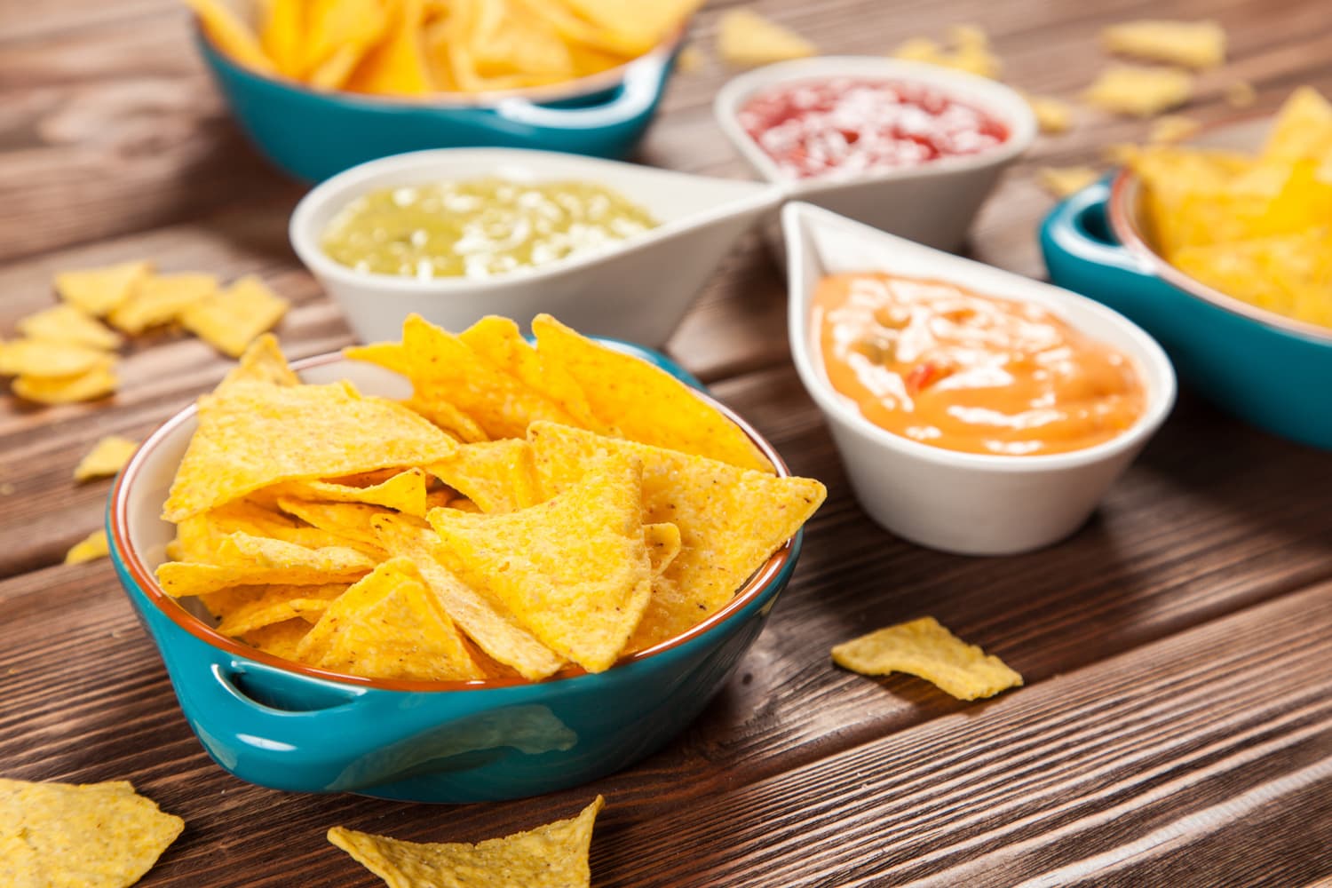 Plate of nachos with salsa, cheese and guacamole dips