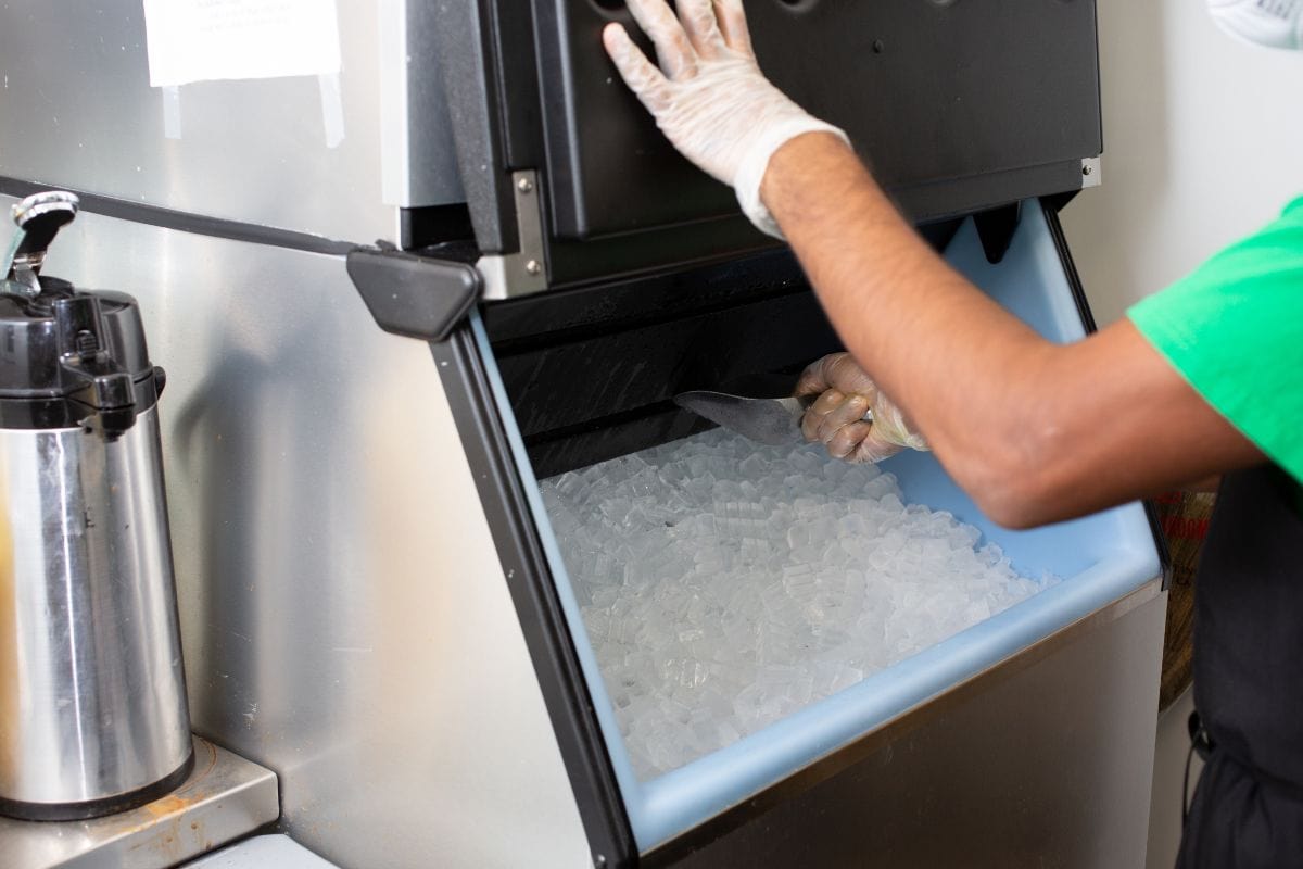 在餐厅里，一名员工从制冰机里舀冰。