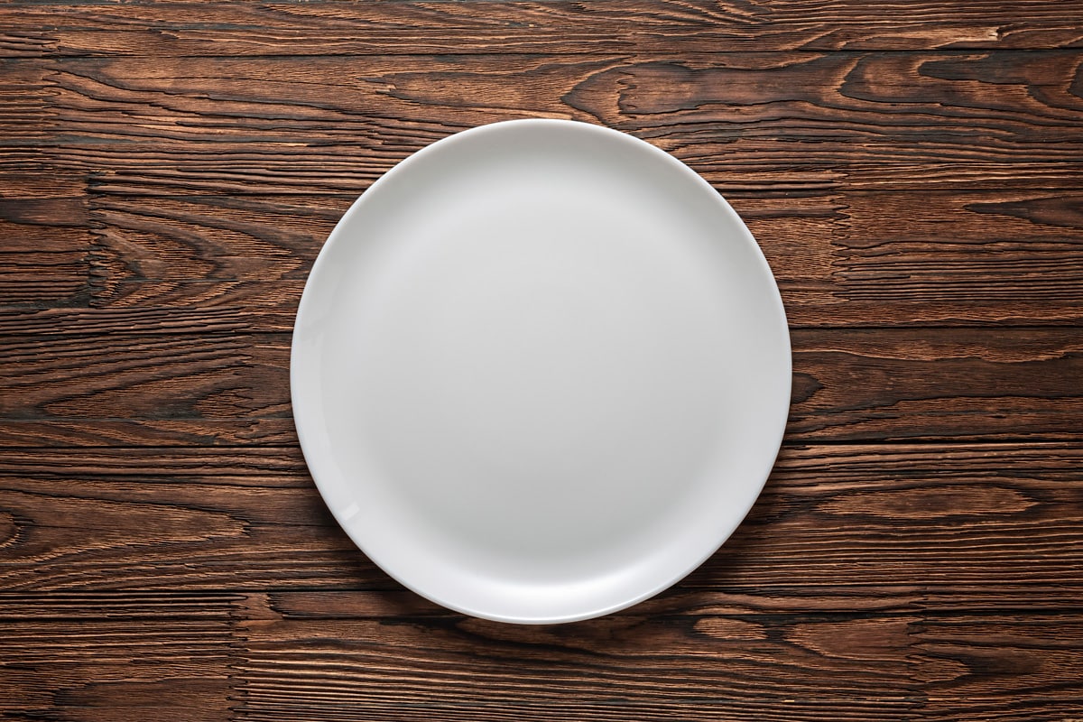 木桌上的白色空盘子。